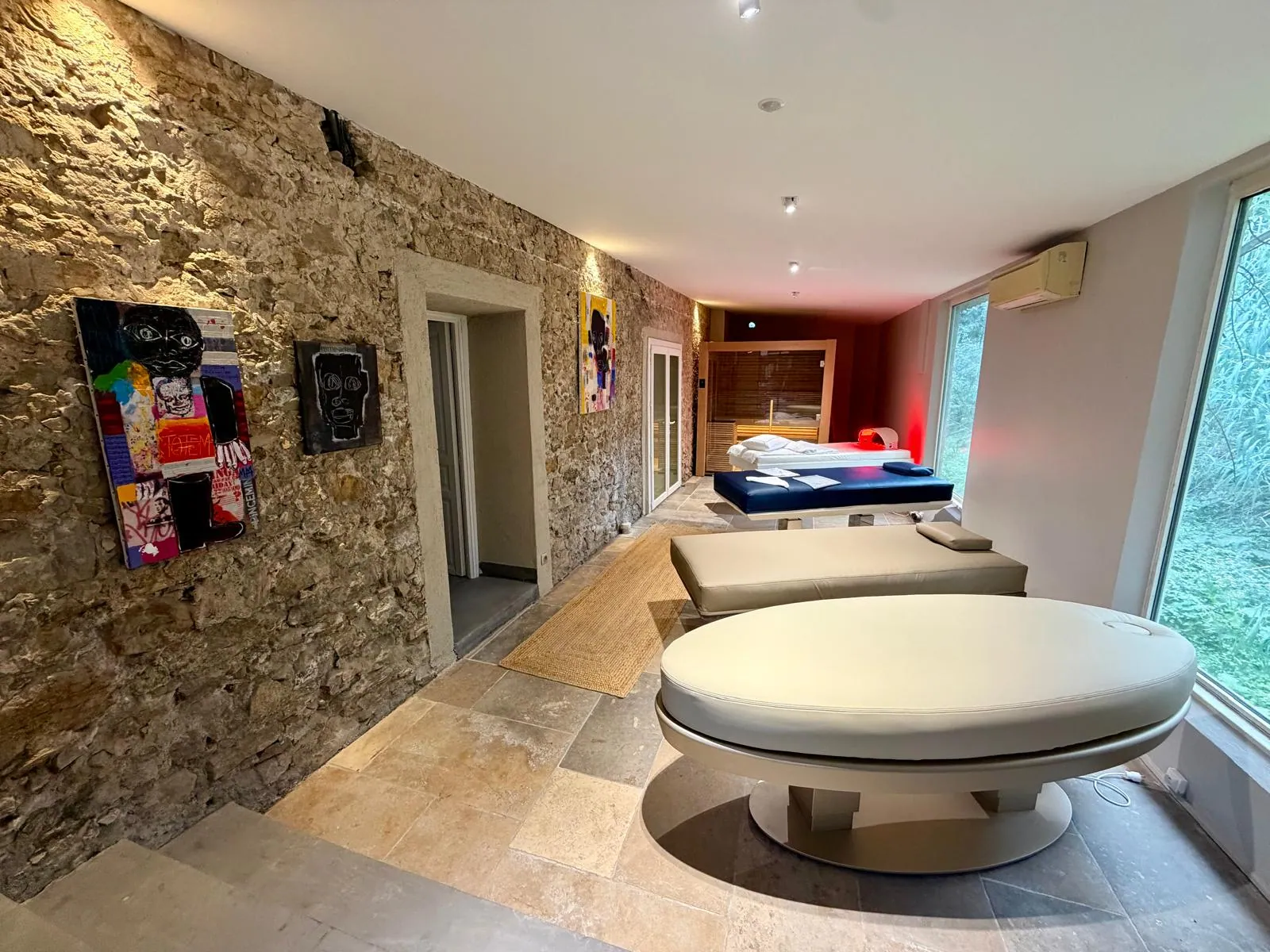 Espace spa du showroom Nöje avec mur en pierre, lit de flottaison et tables de soin