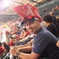 Man wearing an Arizona Cardinals foam hat and smiling in a crowded stadium.