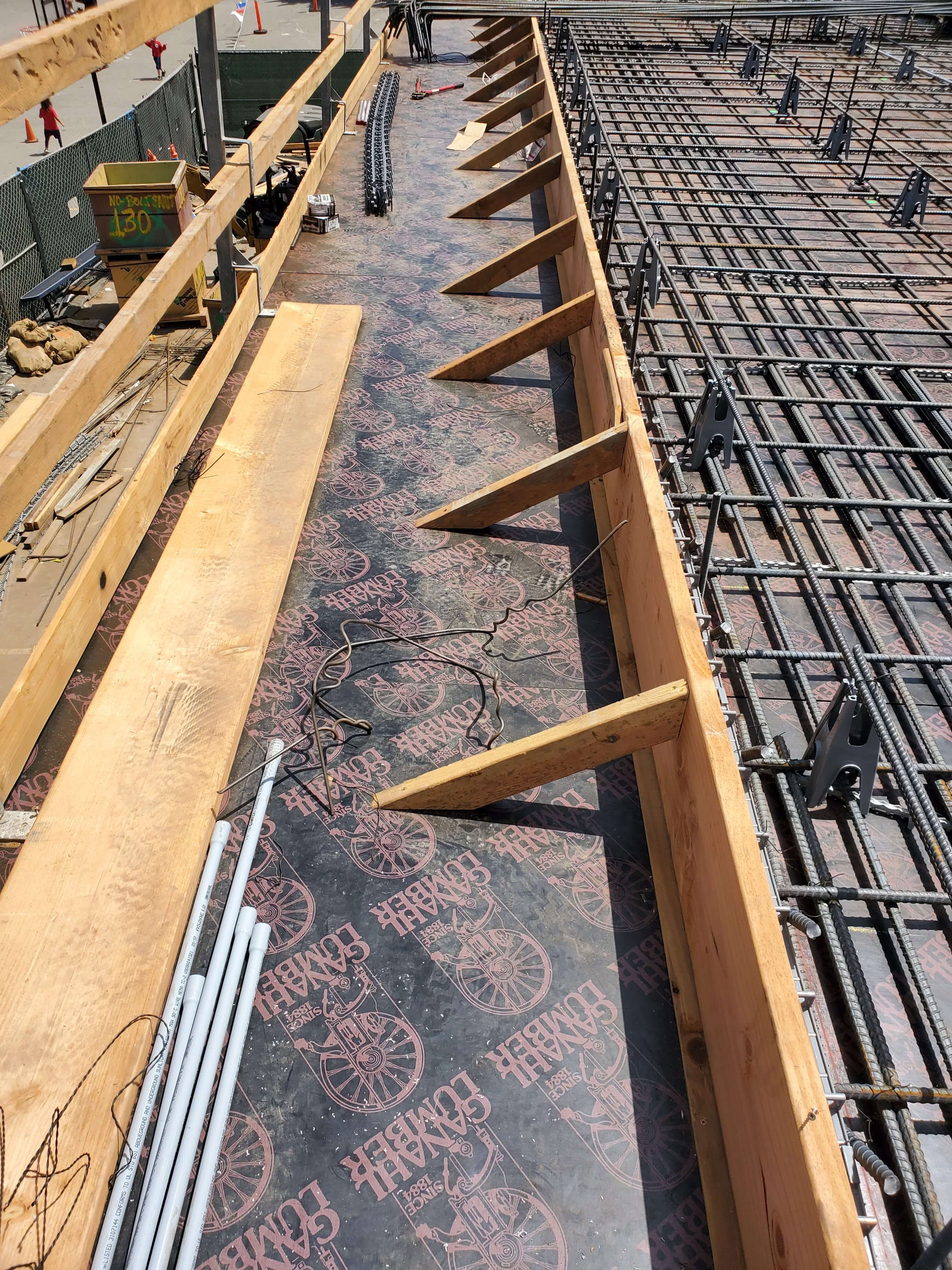 Construction site showing wooden formwork and metal rebar grid for concrete pouring.