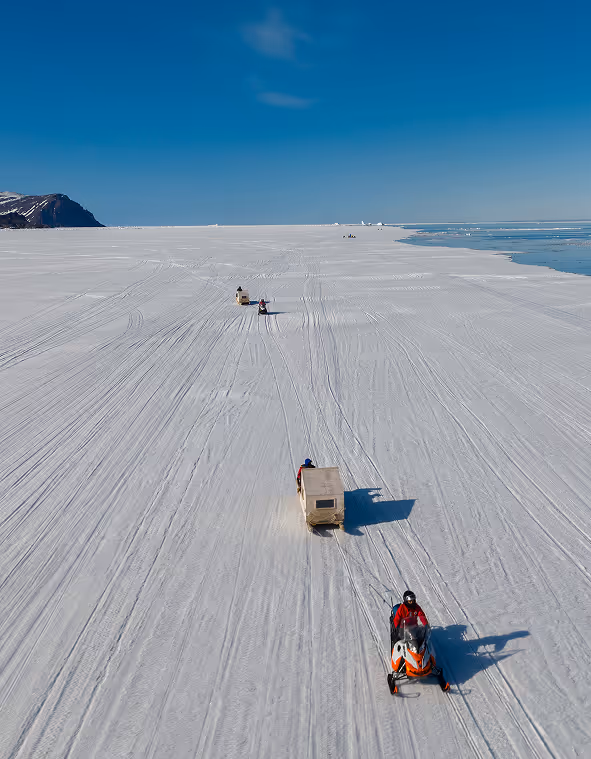 An overhead shot of sleds pulling carts over snow 