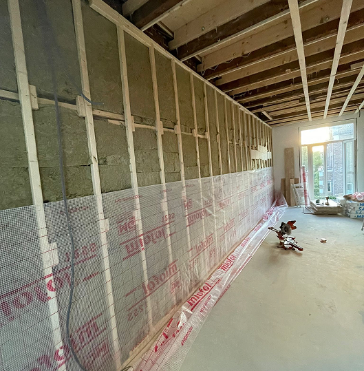 Modern kitchen with white cabinetry, black backsplash, built-in oven and microwave, and brown countertop under warm lighting.
