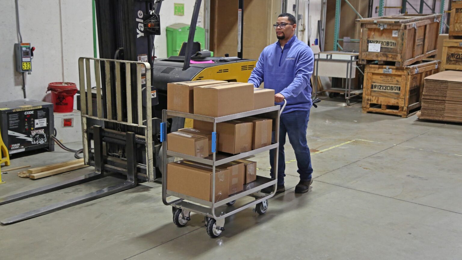 Man, pushing cart with boxes on it in a warehouse