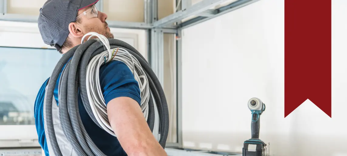 Technician carrying electrical conduit and tools during commercial equipment installation.