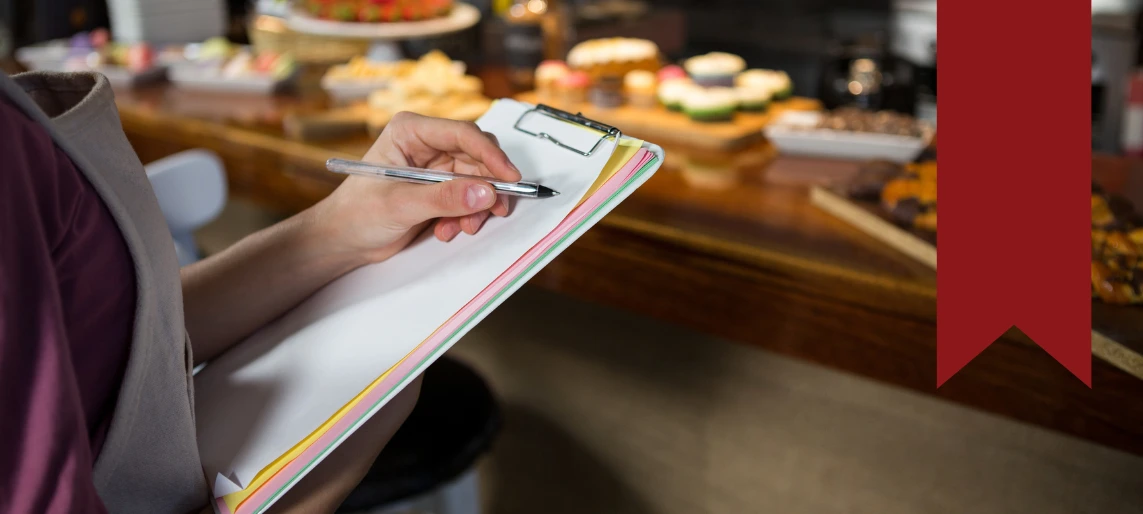 Cannabis kitchen staff member completing compliance checklist and recordkeeping documentation to maintain food safety and regulatory standards with Aldevra.