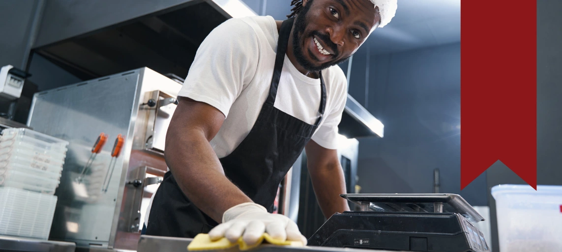 Cannabis kitchen staff member sanitizing food prep surface to prevent mold contamination and maintain hygienic production standards with Aldevra.