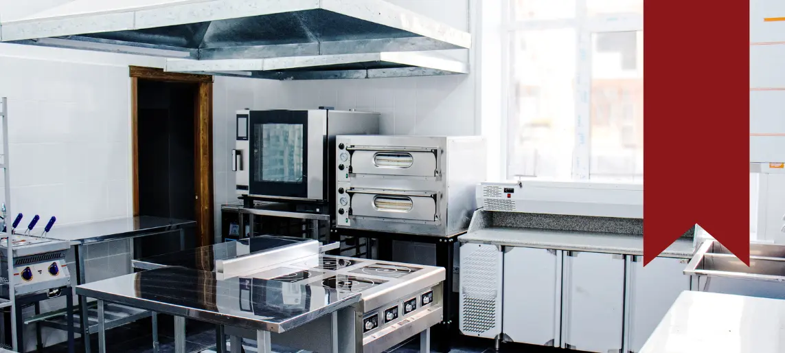 Fully equipped community shared commercial kitchen with ventilation hood, ovens, refrigeration, and stainless prep stations.