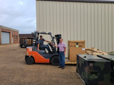 Forklift operator unloading commercial kitchen equipment at a government facility delivery site.