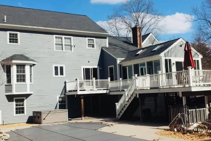 Large residential home with a spacious deck and dark roofing.