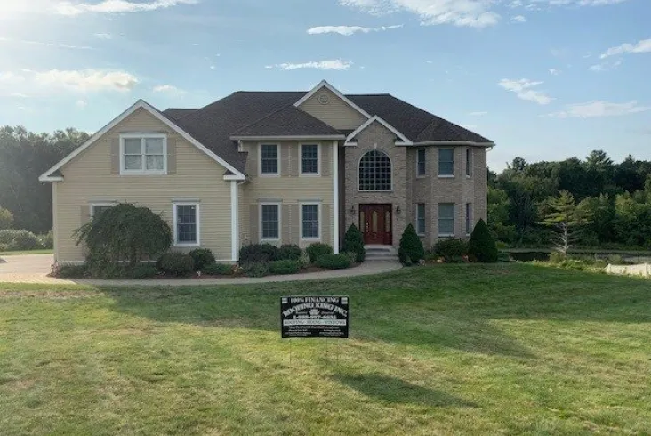 Spacious beige house with a landscaped lawn.