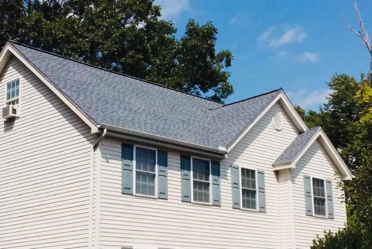 Light-colored house with a new roof and blue shutters.