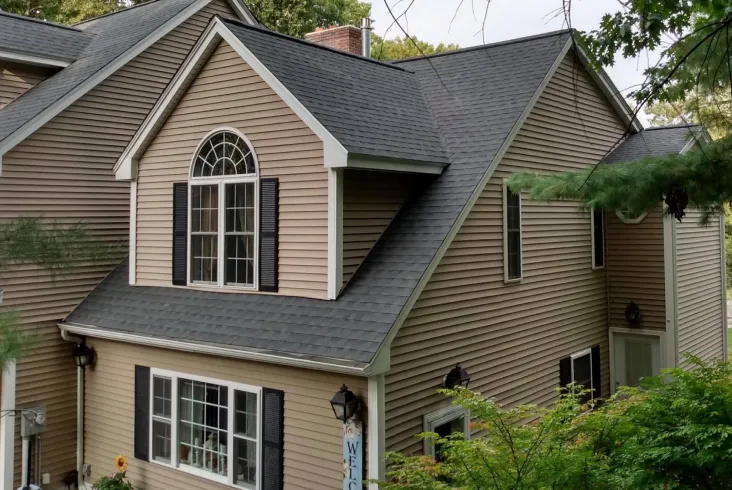 Beige house with a steep roof and large windows.