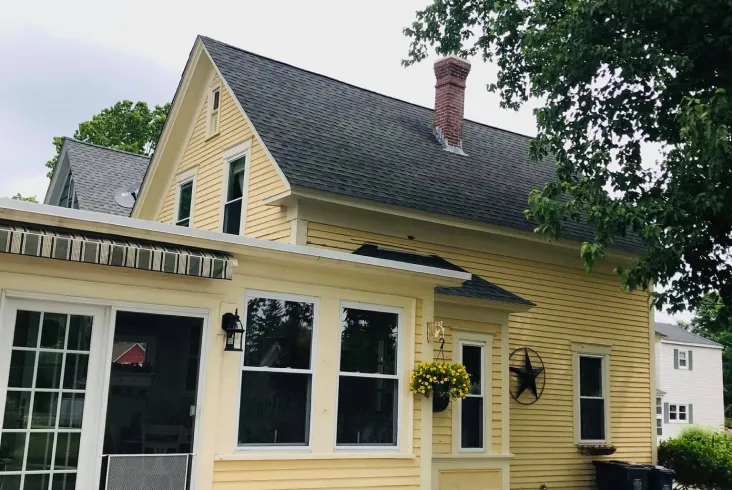 Yellow house with a charming roof and brick chimney.