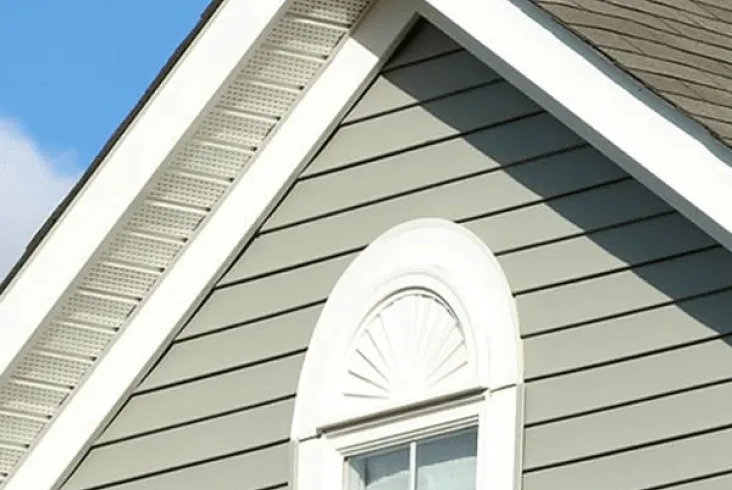 Close-up of a house gable with detailed siding and a window.