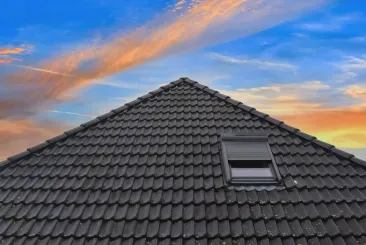 House with a black tile roof against a sunset sky in Gloucester, MA.