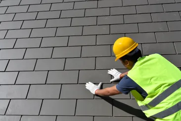 Worker installing slate tiles on a roof in Burlington, MA
