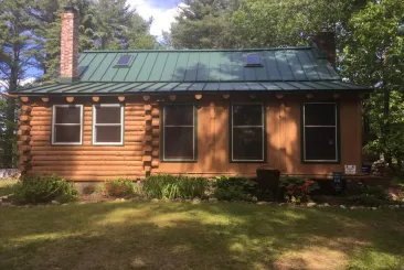 Cabin with a green metal roof in Hudson, NH.
