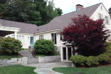 Cozy house with a brown roof and lush greenery in Tewksbury, MA.
