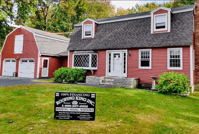 Red house with updated siding and a Roofing King Inc. sign.