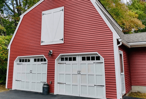 Close-up of red garage with white doors and new siding.