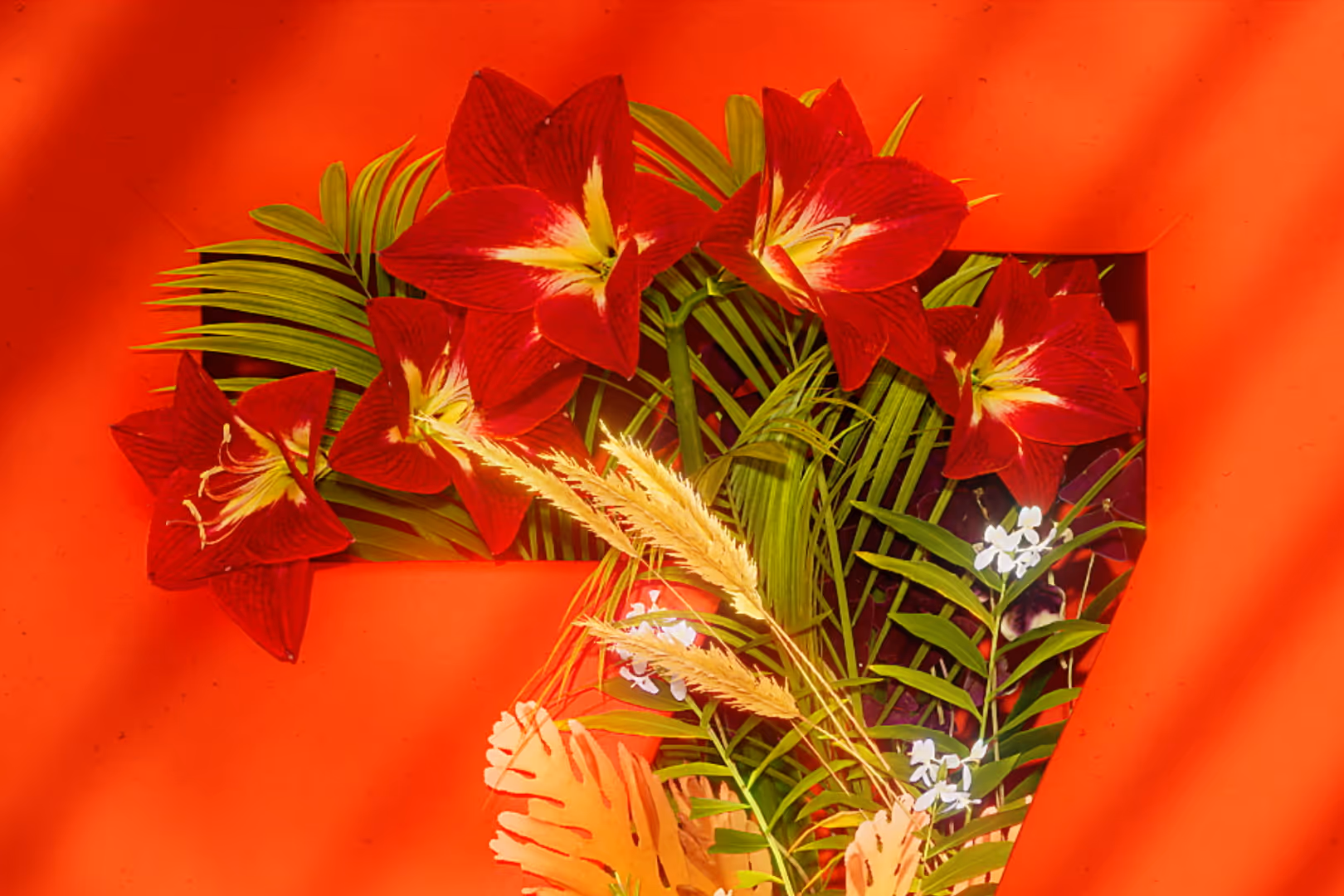 Punaisia amaryllis-kukkia ja vihreitä lehtiä kirkkaan oranssilla taustalla.