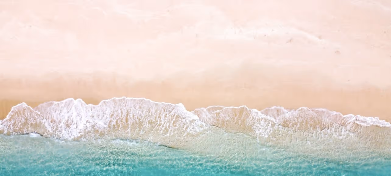 Soft ocean waves rolling onto a sandy beach with turquoise water.  
