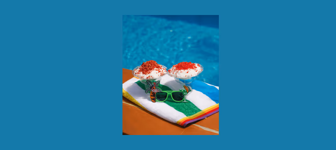 two servings of dessert with red sprinkles on a towel and sunglasses by a pool
