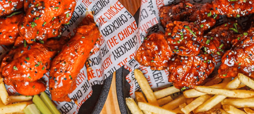 close-up of two servings of chicken wings and french fries