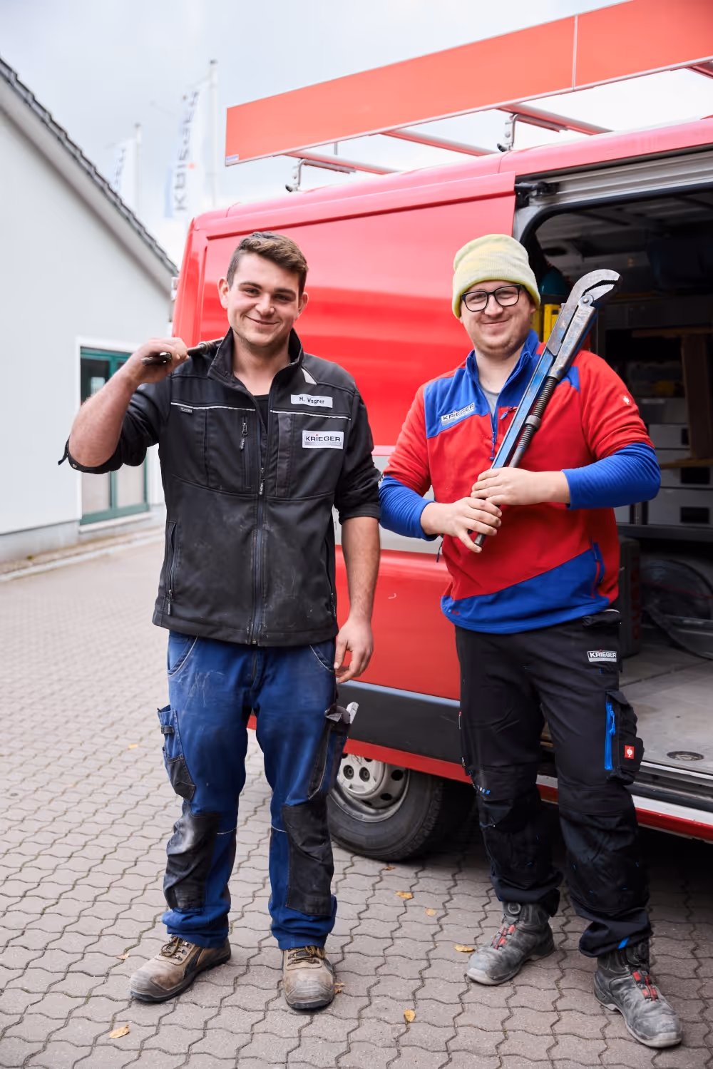 Zwei Krieger Mitarbeiter mit Werkzeugen vor geöffneten Firmenwagen