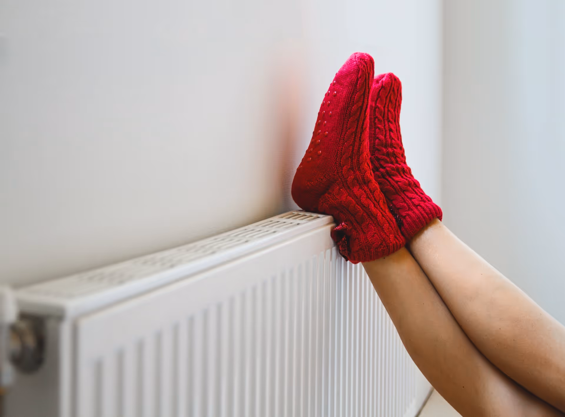 Ausschnitt Beine mit roten Wollsocken auf einer Heizung liegend
