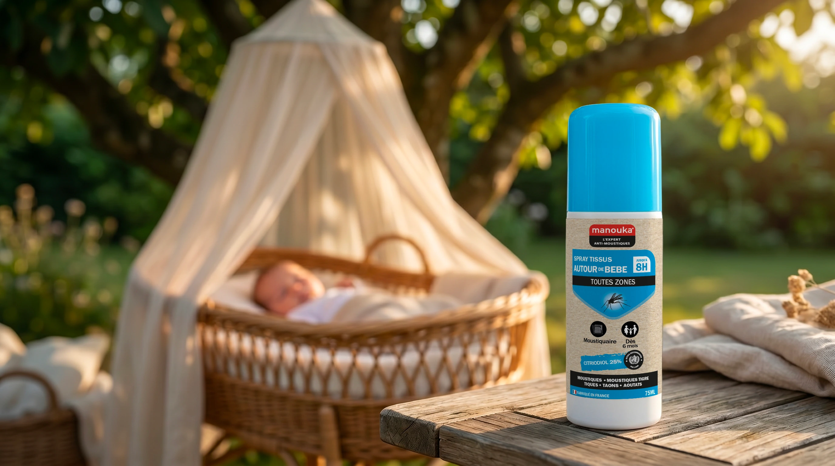 Spray anti-moustiques Manouka pour tissus et moustiquaire autour de bébé posé à proximité d'un berceau en extérieur