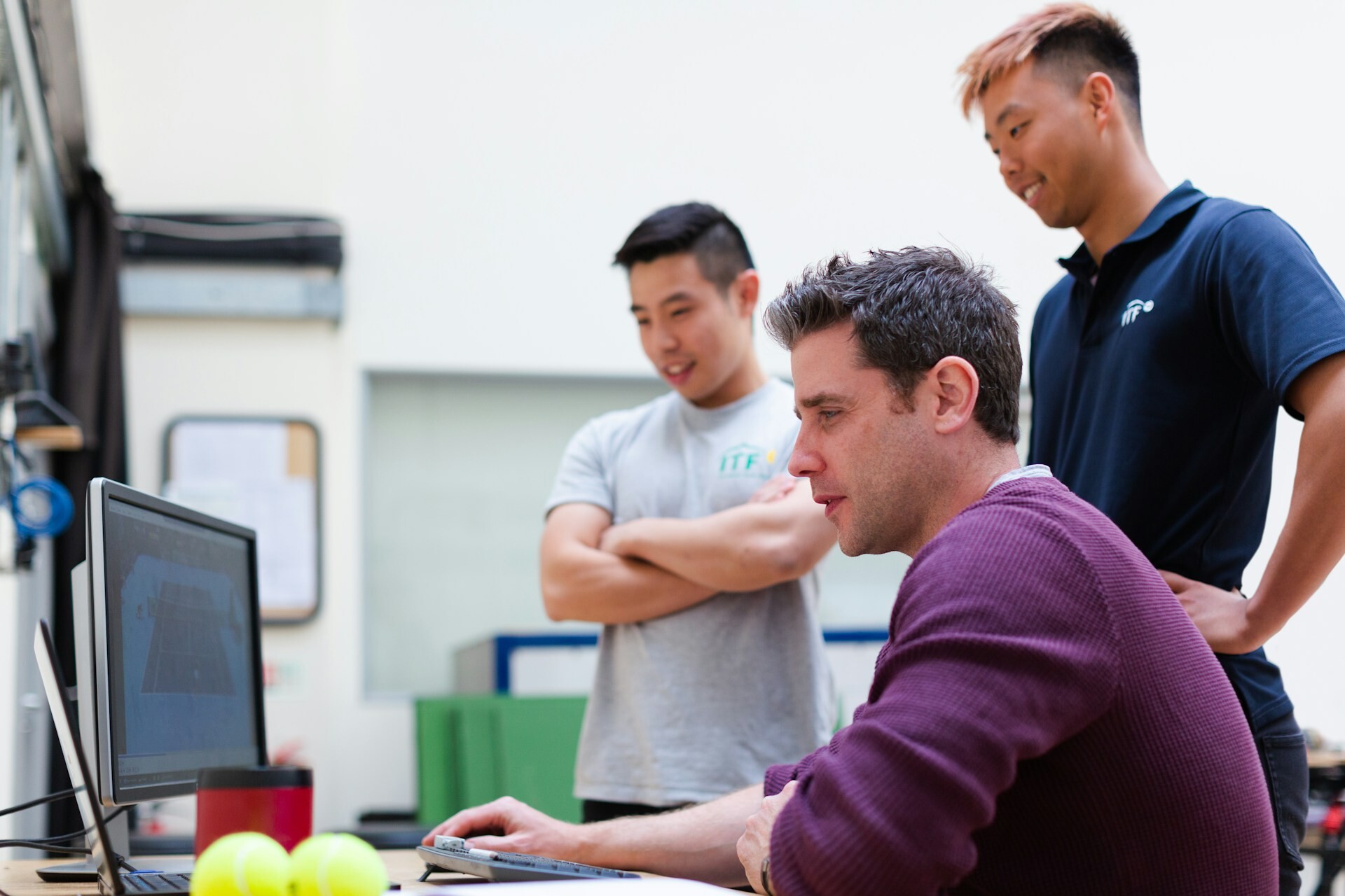 three people looking at a screen in an office