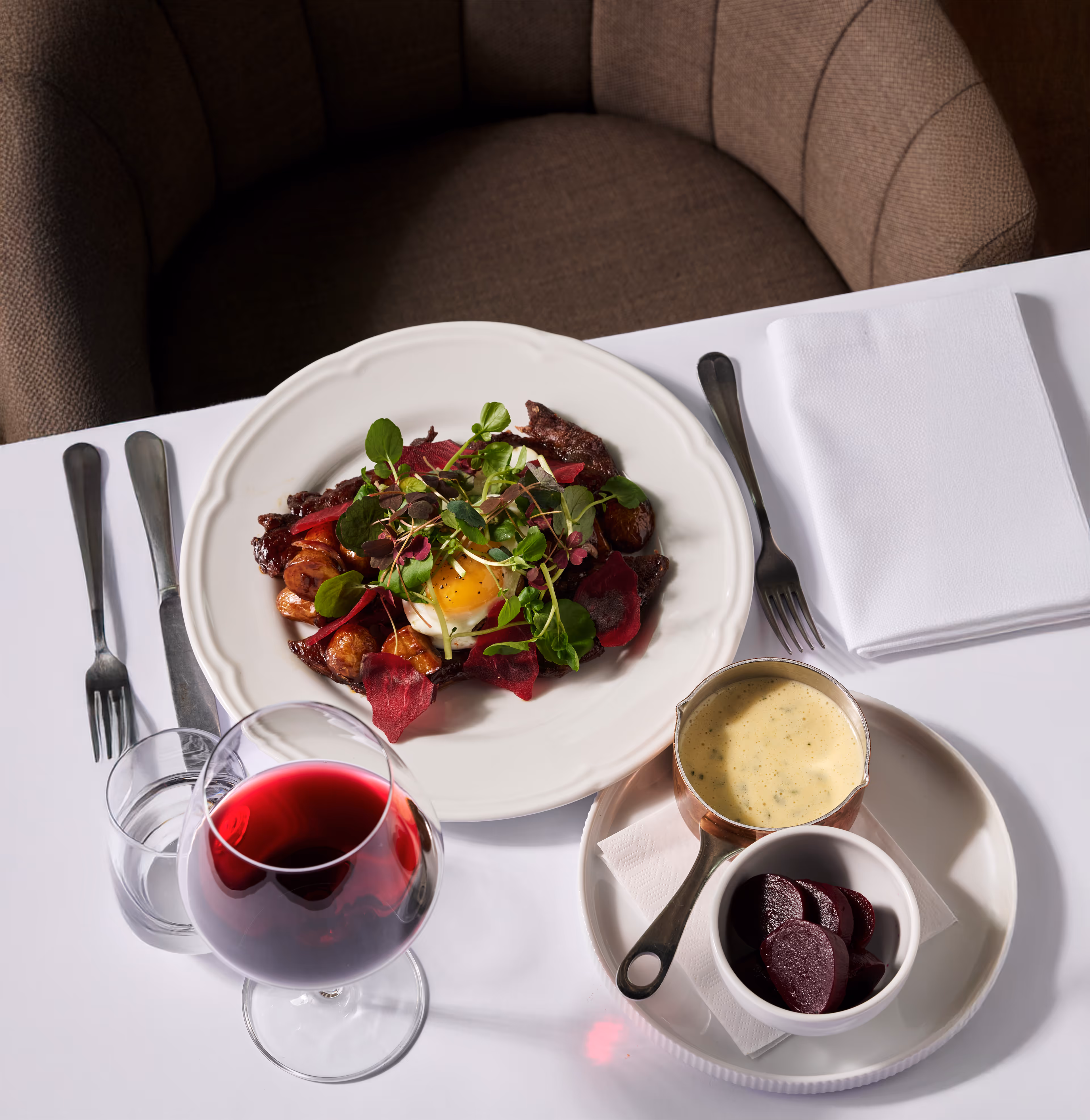 Glazed beef with onions, potatoes, fried egg, and béarnaise sauce