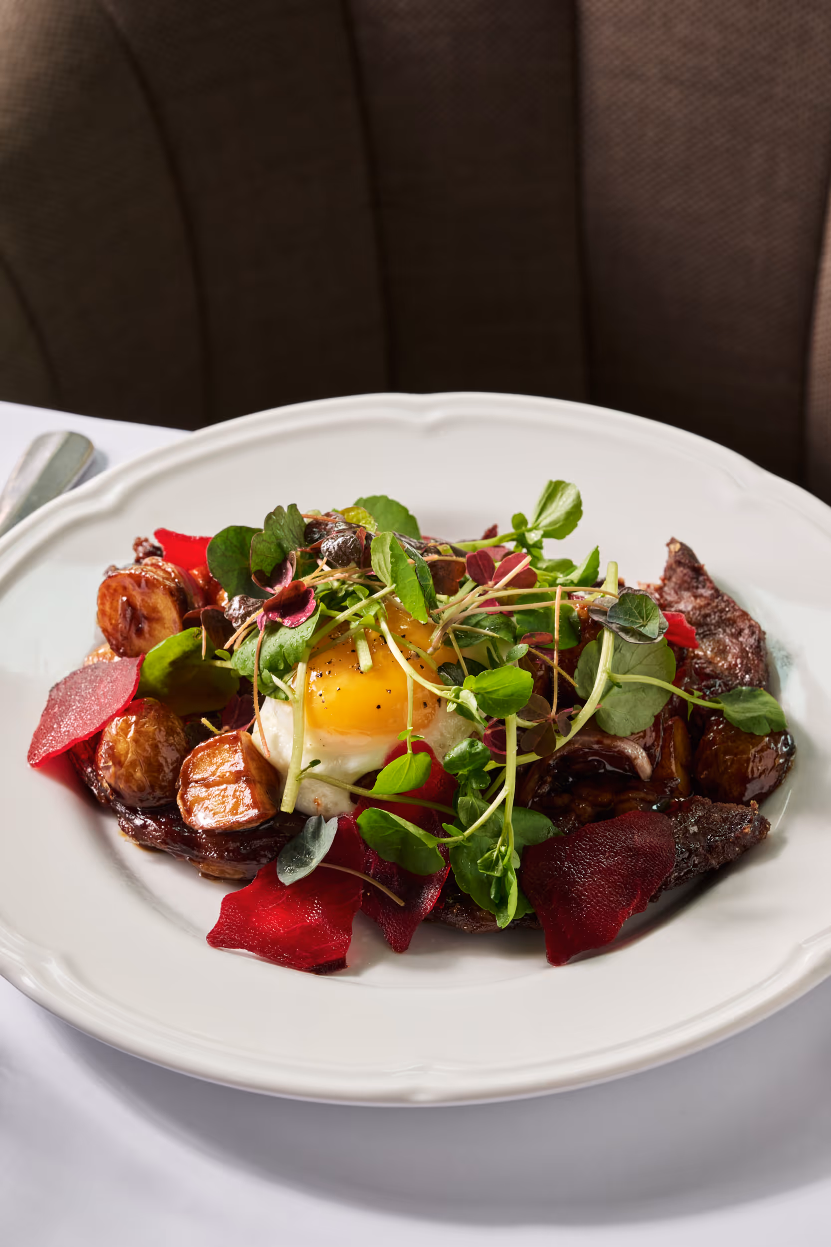 Glazed beef with onions, potatoes, fried egg, and béarnaise sauce