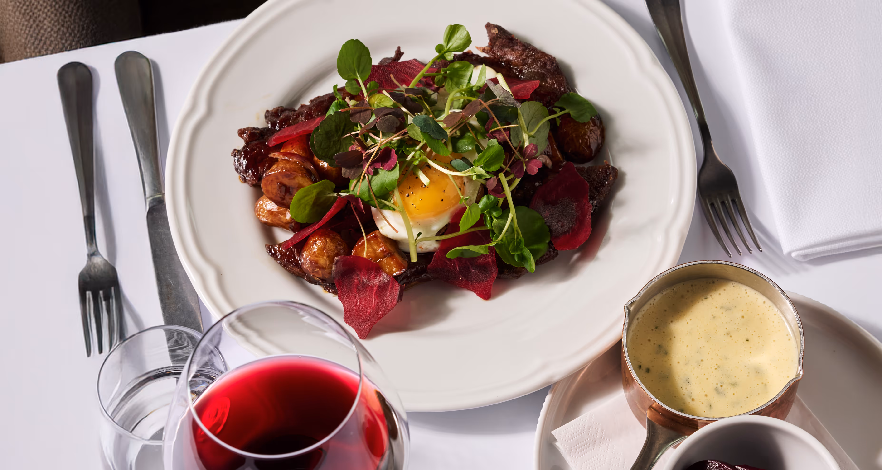 Glazed beef with onions, potatoes, fried egg, and béarnaise sauce