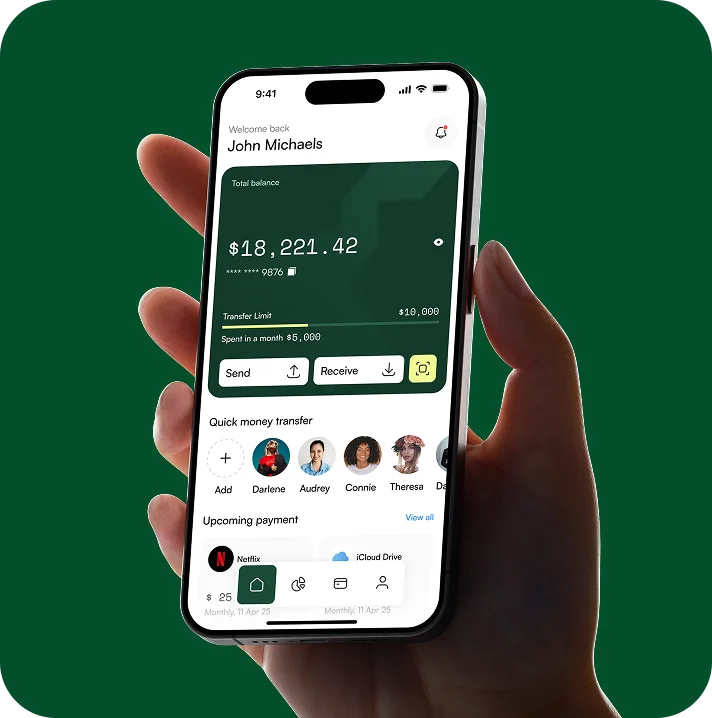 Hand holding a smartphone displaying a banking app with a total balance of $18,221.42 and options to send or receive money.