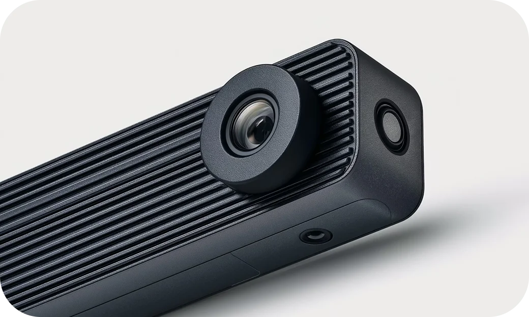 Close-up of a modern black rectangular device with a prominent circular lens, likely a webcam, featuring horizontal ridges on its body.