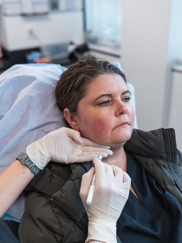 Woman receiving a cosmetic facial injection from a professional wearing white gloves.