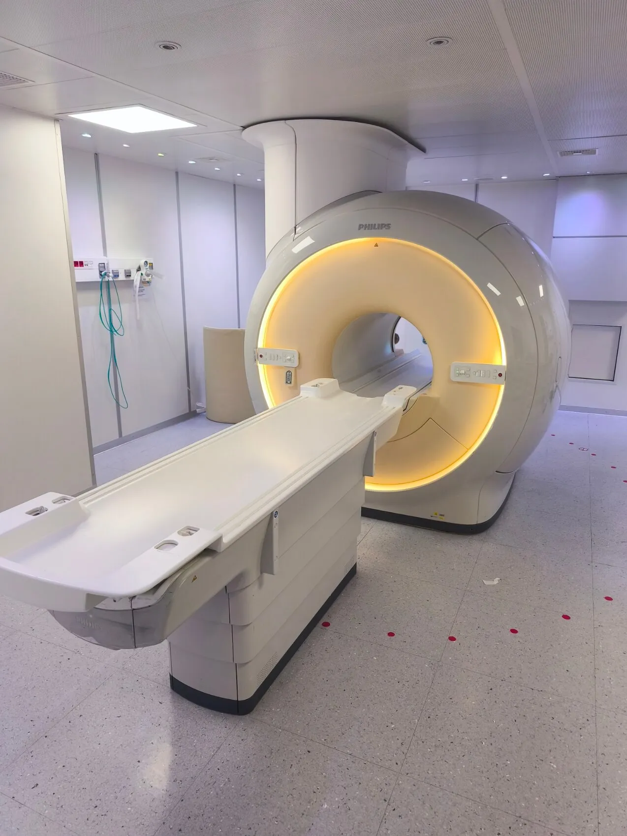 Philips MRI scanner machine in a clean, well-lit hospital room with a white patient bed and circular scanning tunnel.