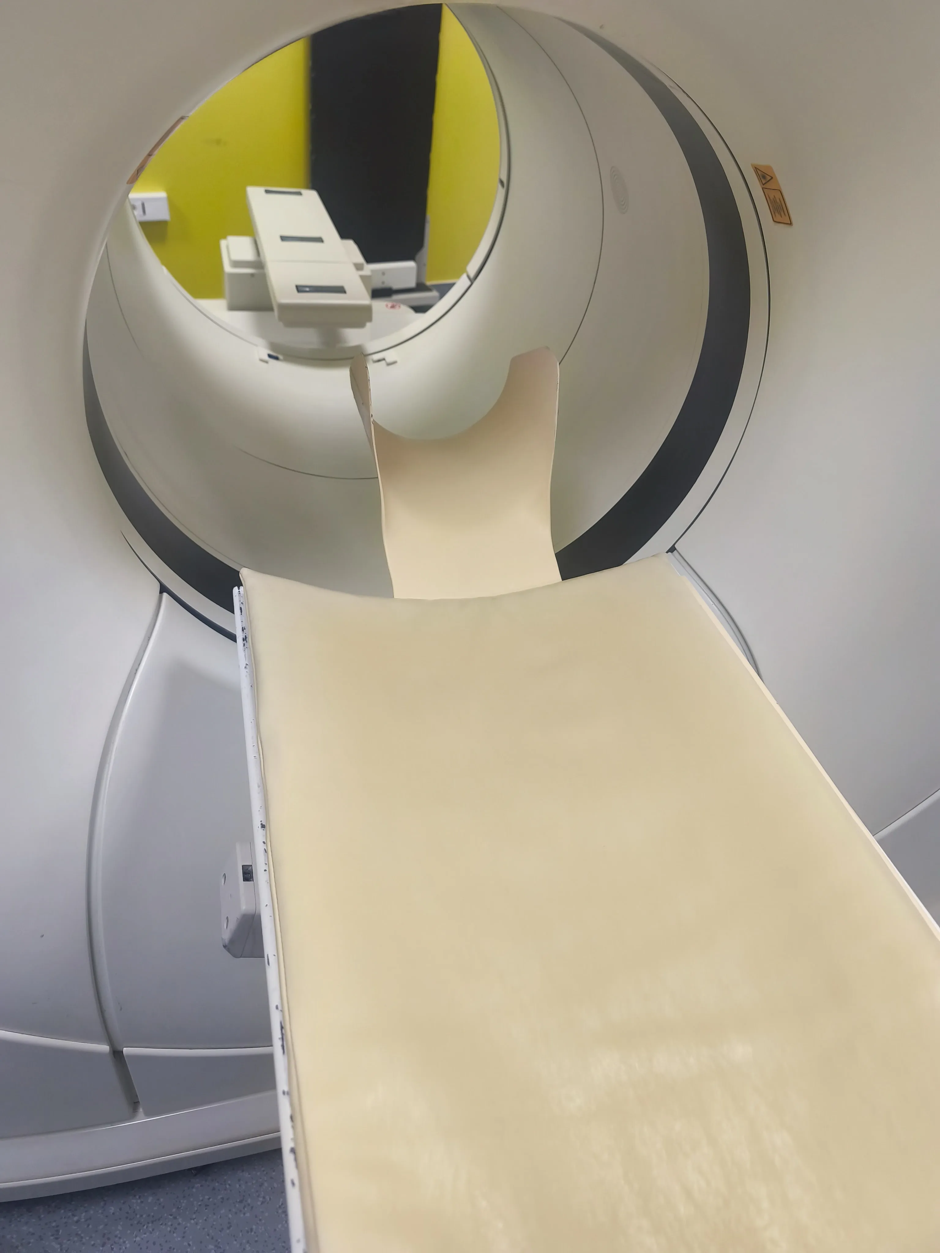 Interior view of a CT scan machine with a beige patient table extending into the circular scanning area.