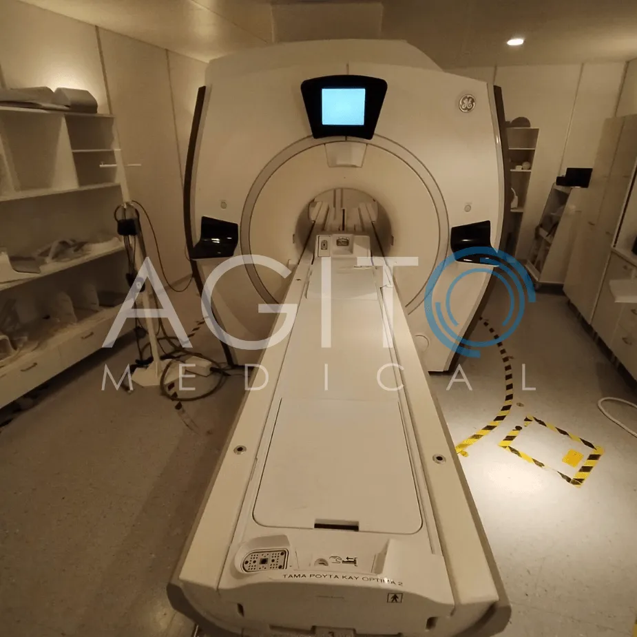 MRI machine in a medical imaging room with shelves and equipment on the sides.