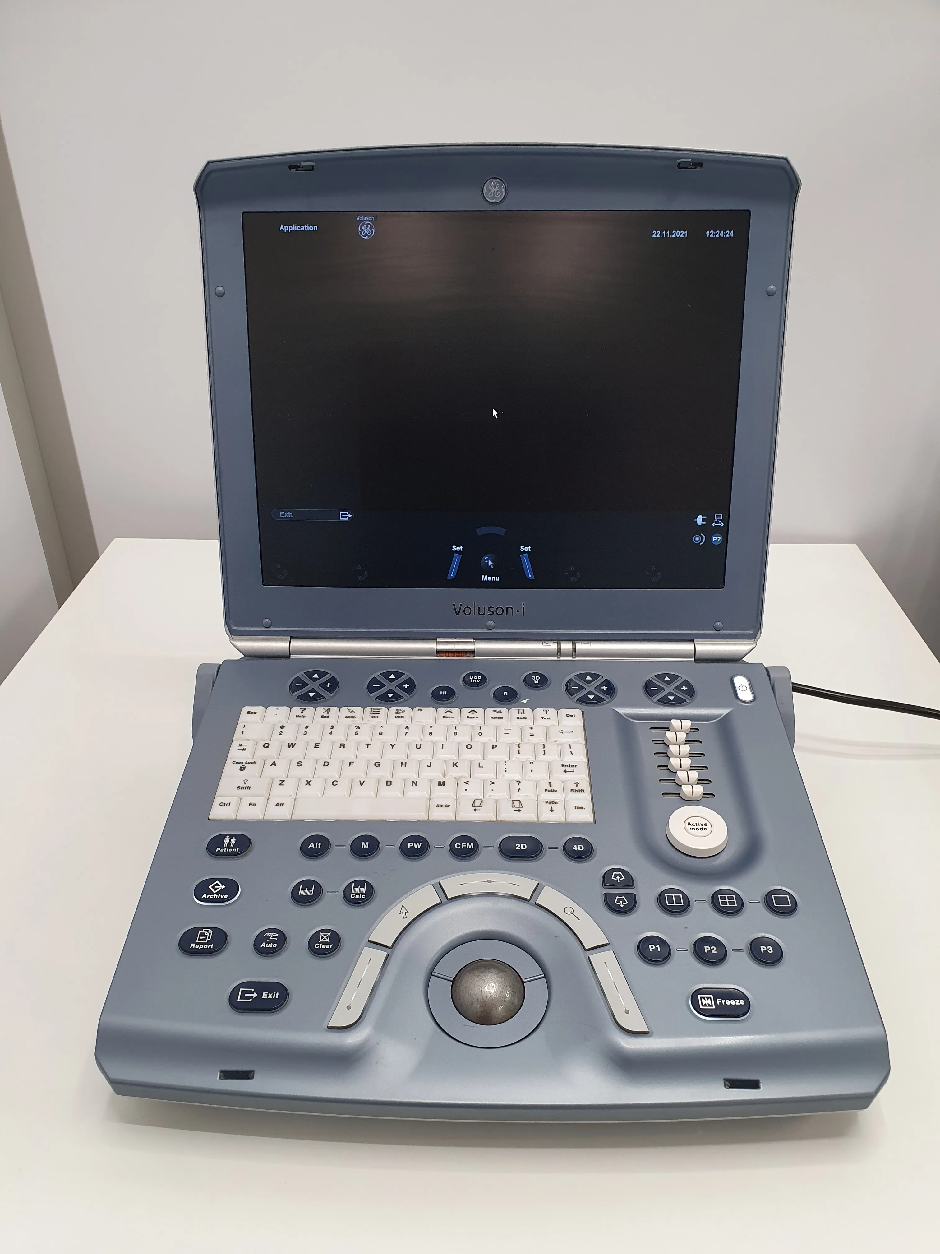 GE Voluson i ultrasound machine with screen, keyboard, control buttons, and trackball on a white table.