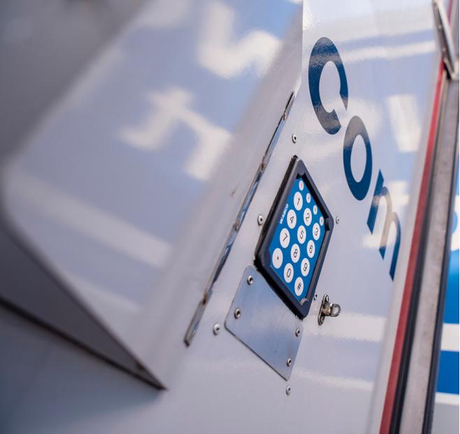 Close-up of a numeric keypad mounted on a metal door with partial blue text 'Con'.