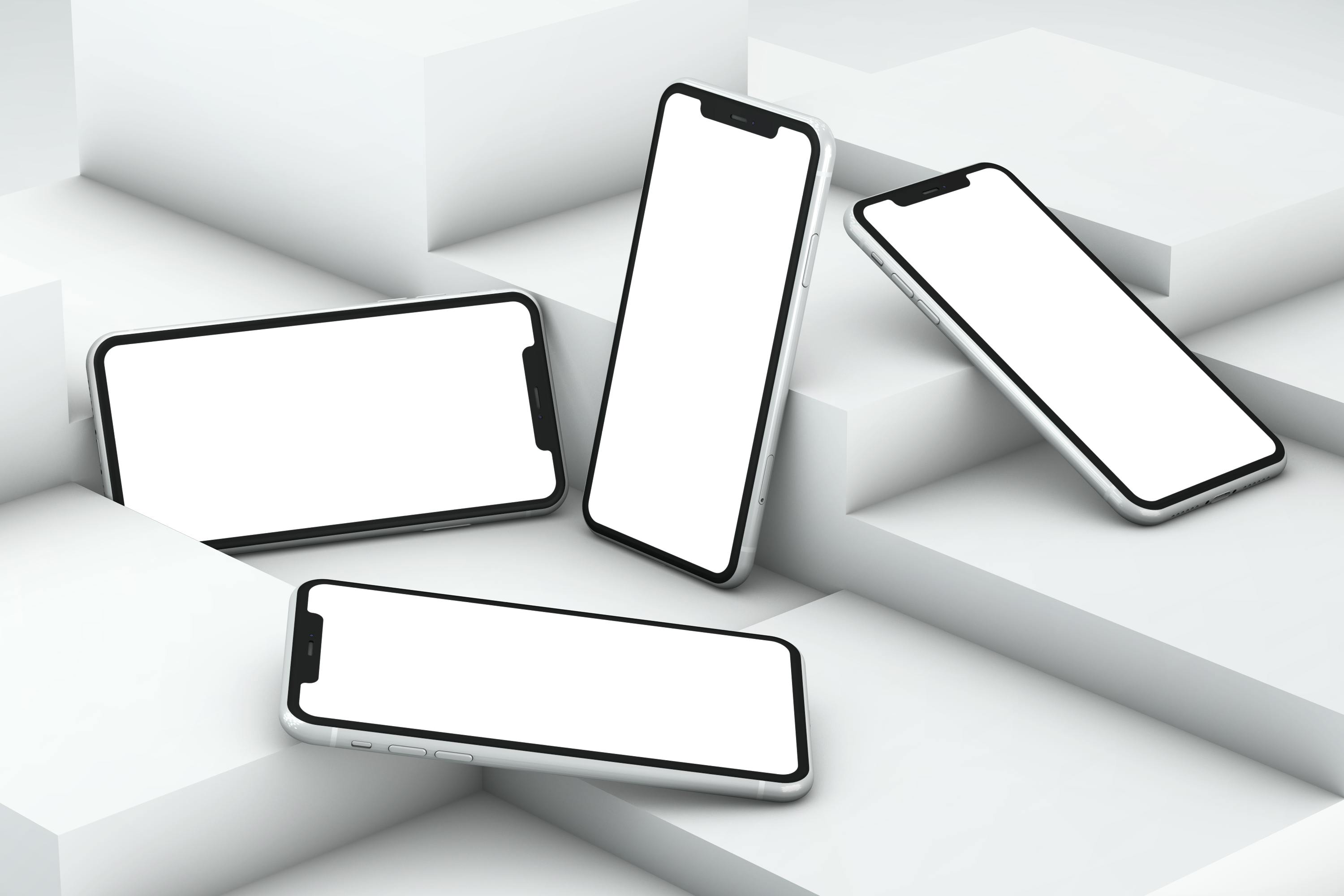 Four modern smartphones with blank white screens arranged on white geometric blocks.