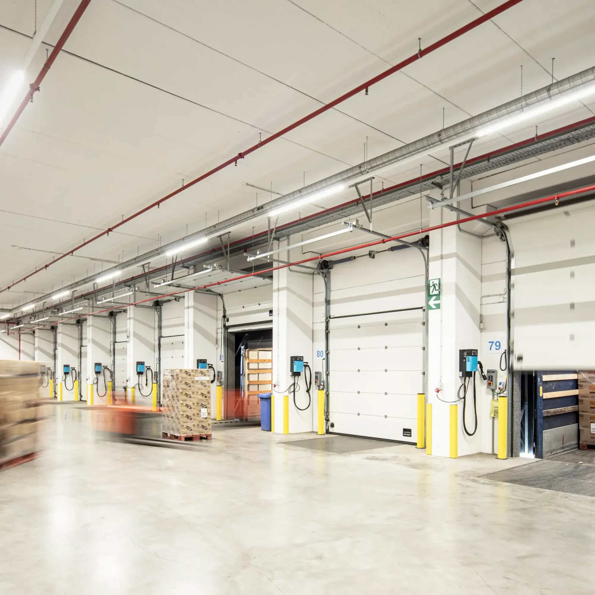 Warehouse loading docks with pallets and motion blur indicating moving forklift.