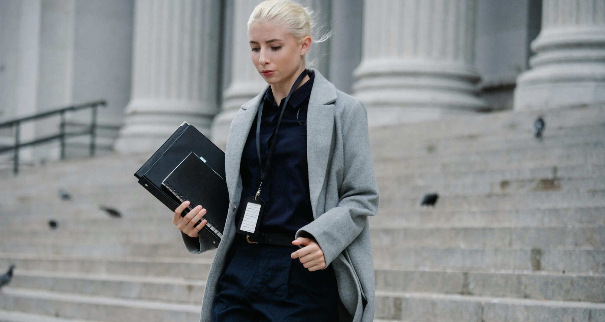 Une femme marchant dans la rue avec un ordinateur portable à la main.