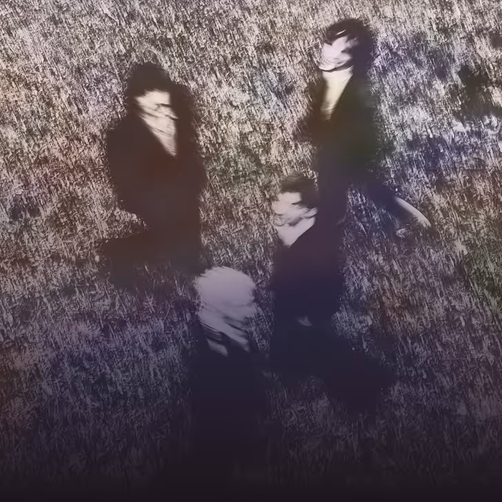 Photo floue de quatre personnes debout, prises d'en haut sur un sol texturé.