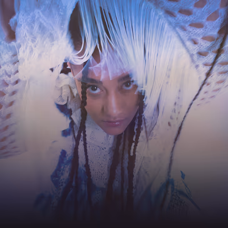 Personne regardant vers le haut avec des tresses et un vêtement en crochet blanc avec franges.