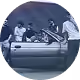 Groupe de personnes autour d'une voiture décapotable en pleine conversation.