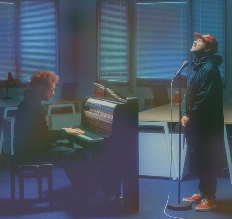 Une personne joue du piano en salle tandis qu'une autre chante devant un micro.