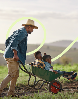 A man in the countryside with a wheelbarrow with children in it.